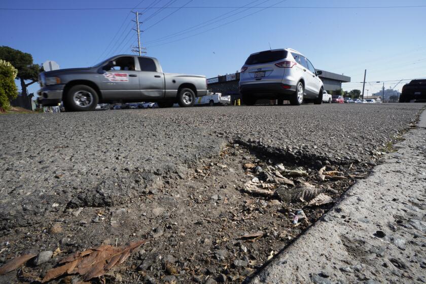 San Diego, CA - January 16: On Tuesday, Jan. 16, 2024, in San Diego, CA, motorists drive past a pothole of crumbling asphalt on the corner of S 27th Street and Boston Avenue. (Nelvin C. Cepeda / The San Diego Union-Tribune)
