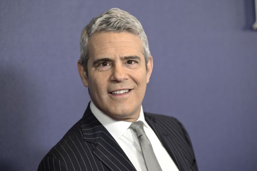 A man with gray hair posing in a black pinstripe suit and gray tie