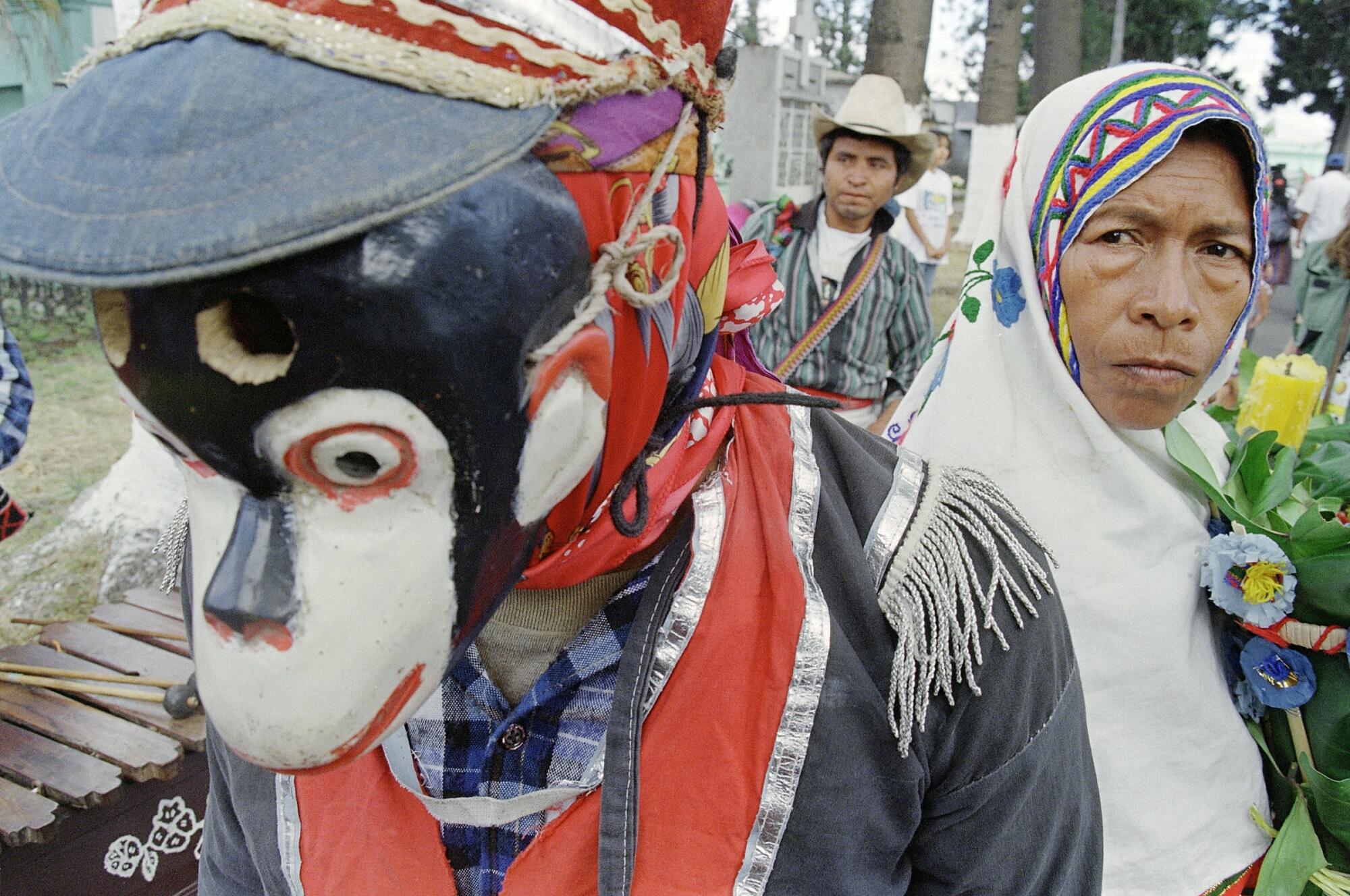 A woman wearing a headscarf and a person wearing a monkey mask