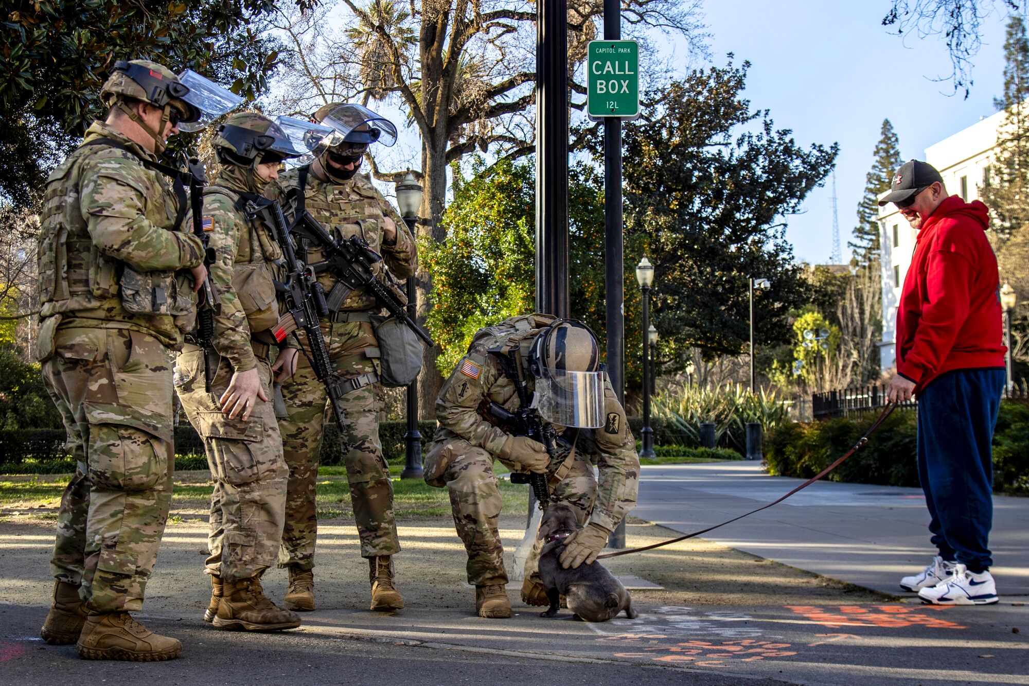 National Guard troops pet a dog on a walk past the California State Capitol.