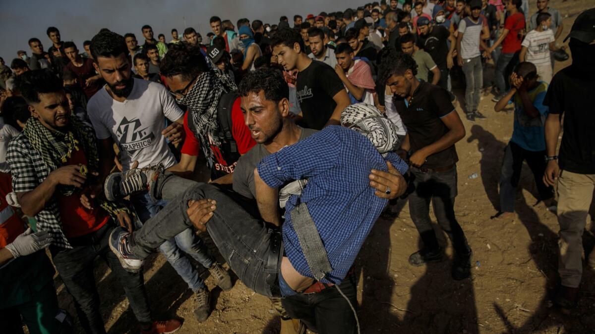 A Palestinian man carries a fellow protester who was shot in the foot by Israeli forces at the border fence separating Israel and the Gaza Strip.