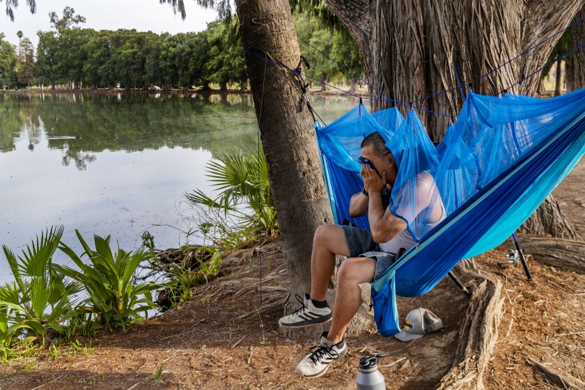RIVERSIDE, CA - AUGUST 18, 2020: Jon Galapago of Riverside wipes the sweat from his face while sitting in a hammock fishing at Lake Evans in triple digit temperatures on August 18, 2020 in Riverside, California. (Gina Ferazzi / Los Angeles Times)