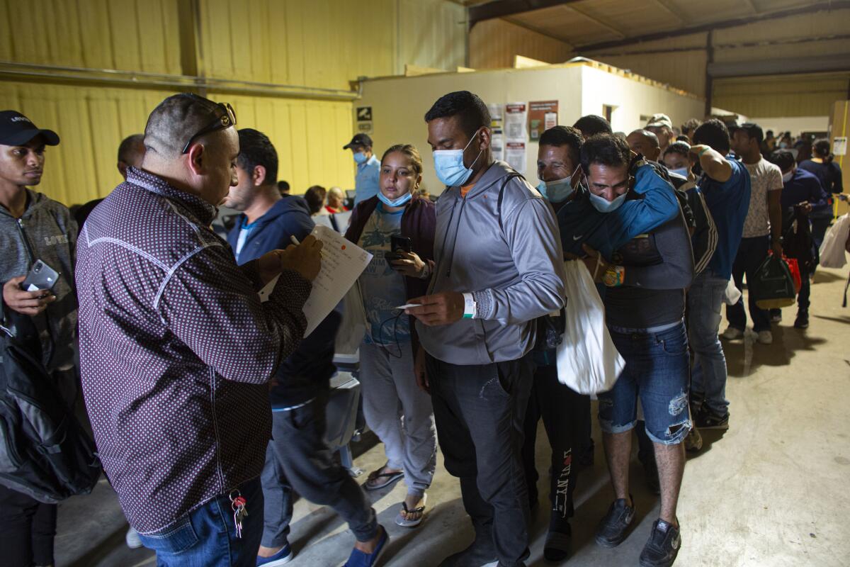 ARCHIVO - Varias personas hacen fila para abordar un autobús que los llevará al aeropuerto de San Antonio 