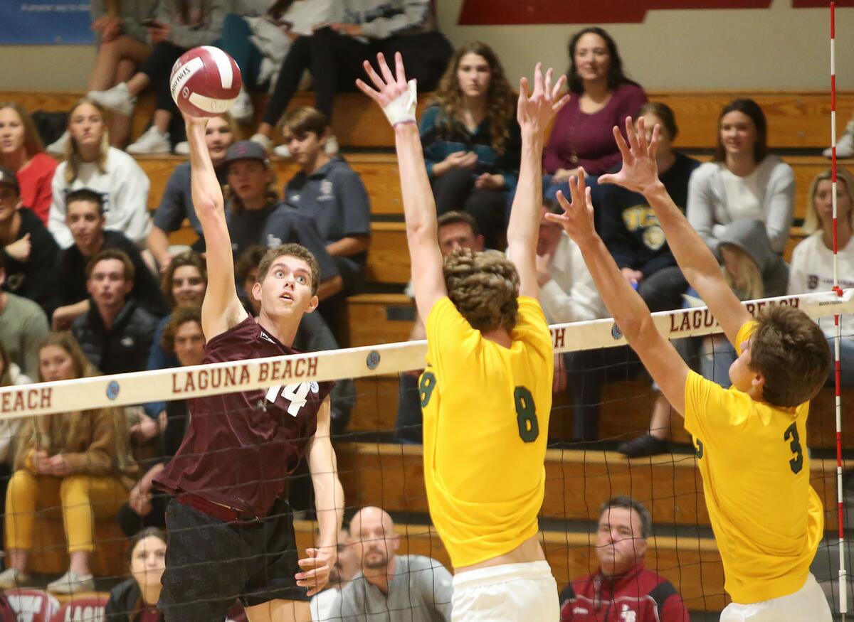 Laguna Beach outside hitter Andrew Reavis records a kill against Mira Costa blockers Dain Johnson (8) and Jack Walmer (3) during a nonleague match at home Wednesday.