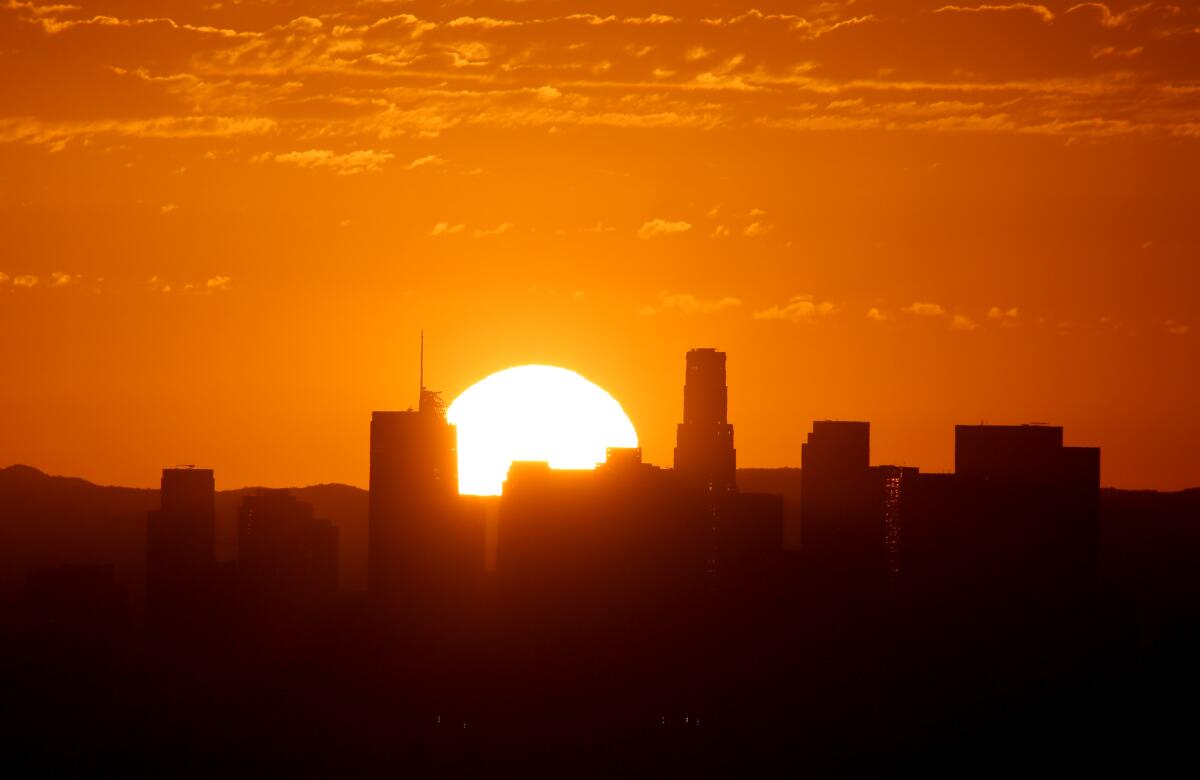 The sun sets between two buildings.