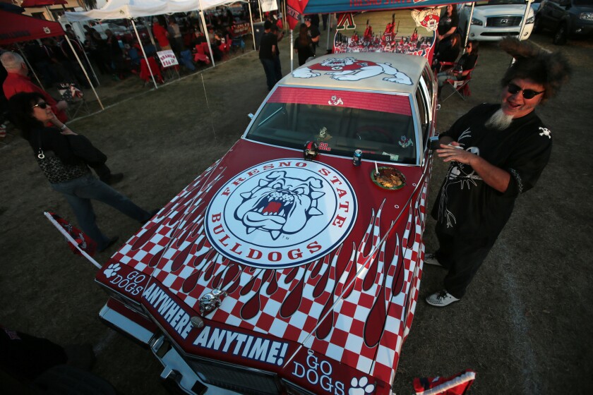 Brian Boever eats off the hood of his custom Cadillac as fans flock to Bulldog Stadium to tailgate and cheer the undefeated Fresno State football team.