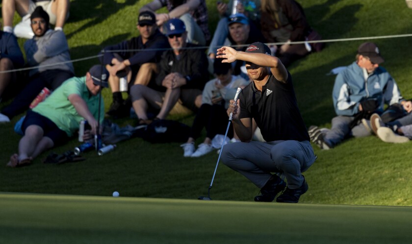 Colin Morikawa shields his eyes from the setting sun on the 18th hole during the second round of the Genesis Invitational.
