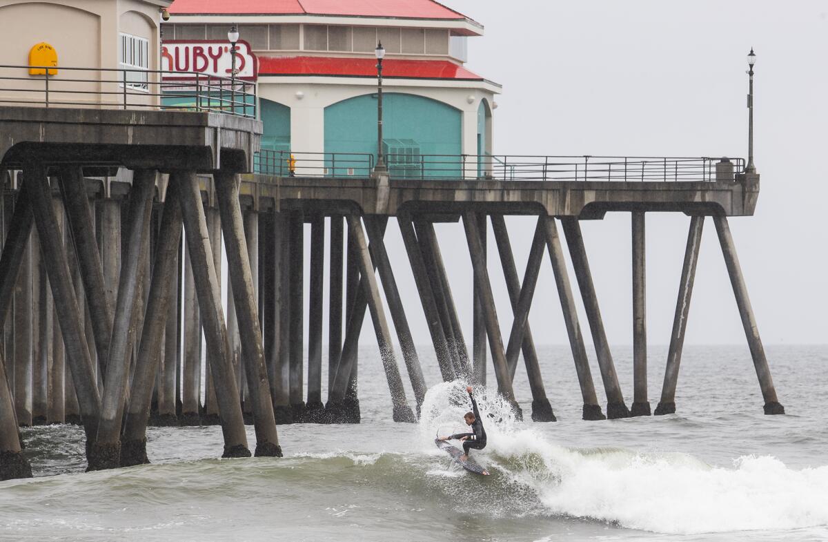 A surfer catches a wave near the Huntington Beach Pier on Thursday.