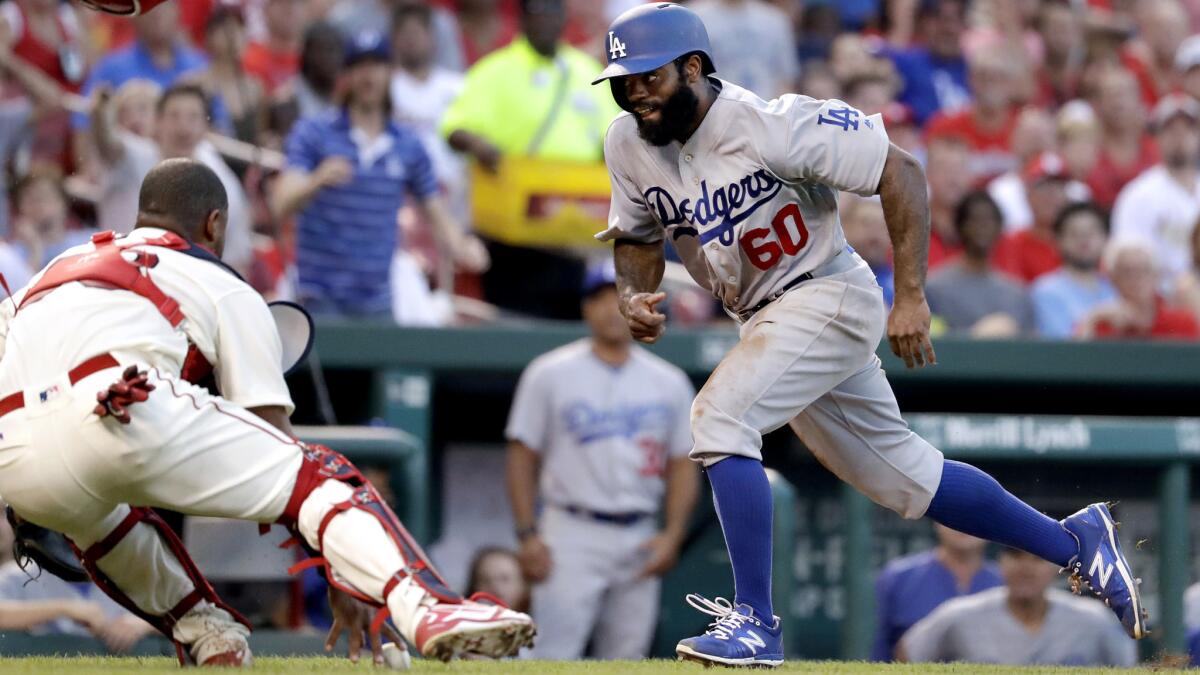 Dodgers right fielder Andrew Toles scores in the sixth inning as catcher Alberto Rosario of the St. Louis Cardinals tries to grab the ball.