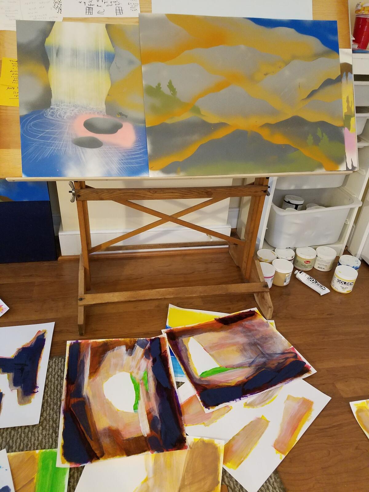 Paintings on a drawing table and the floor around it.