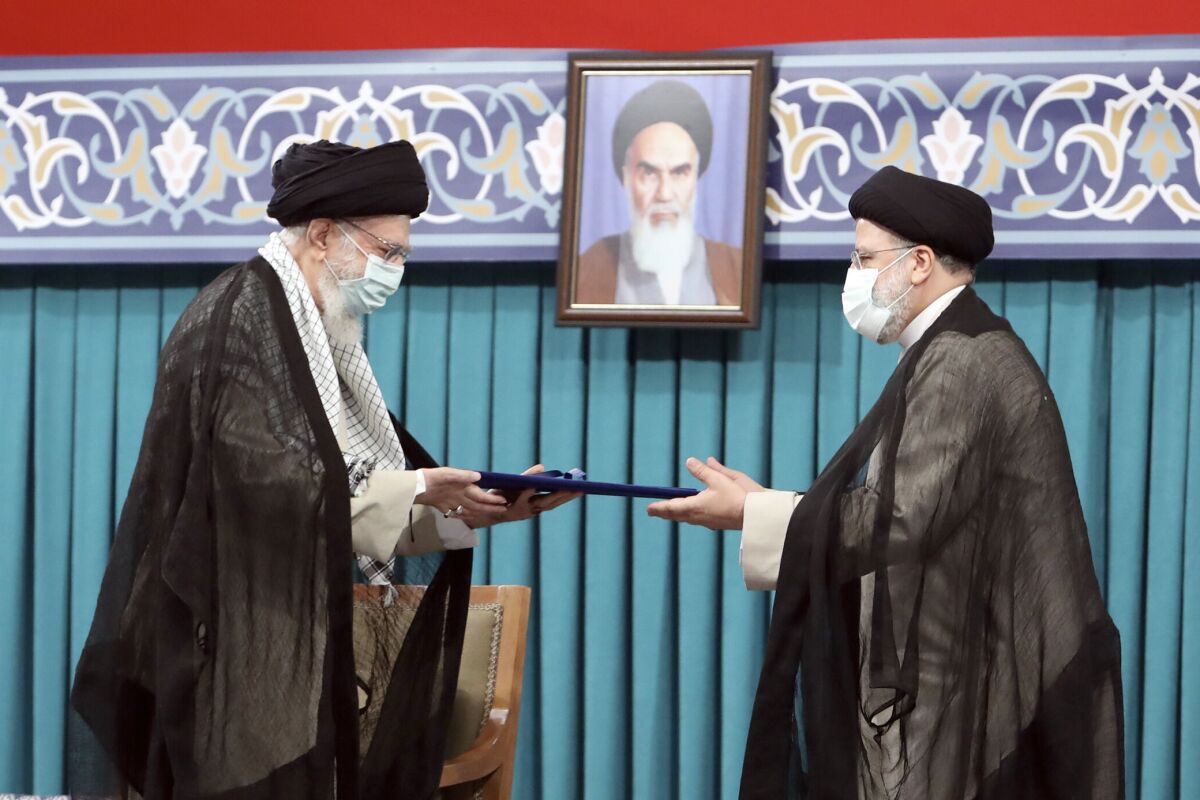 Ayatollah Ali Khamenei hands a document to Ebrahim Raisi.