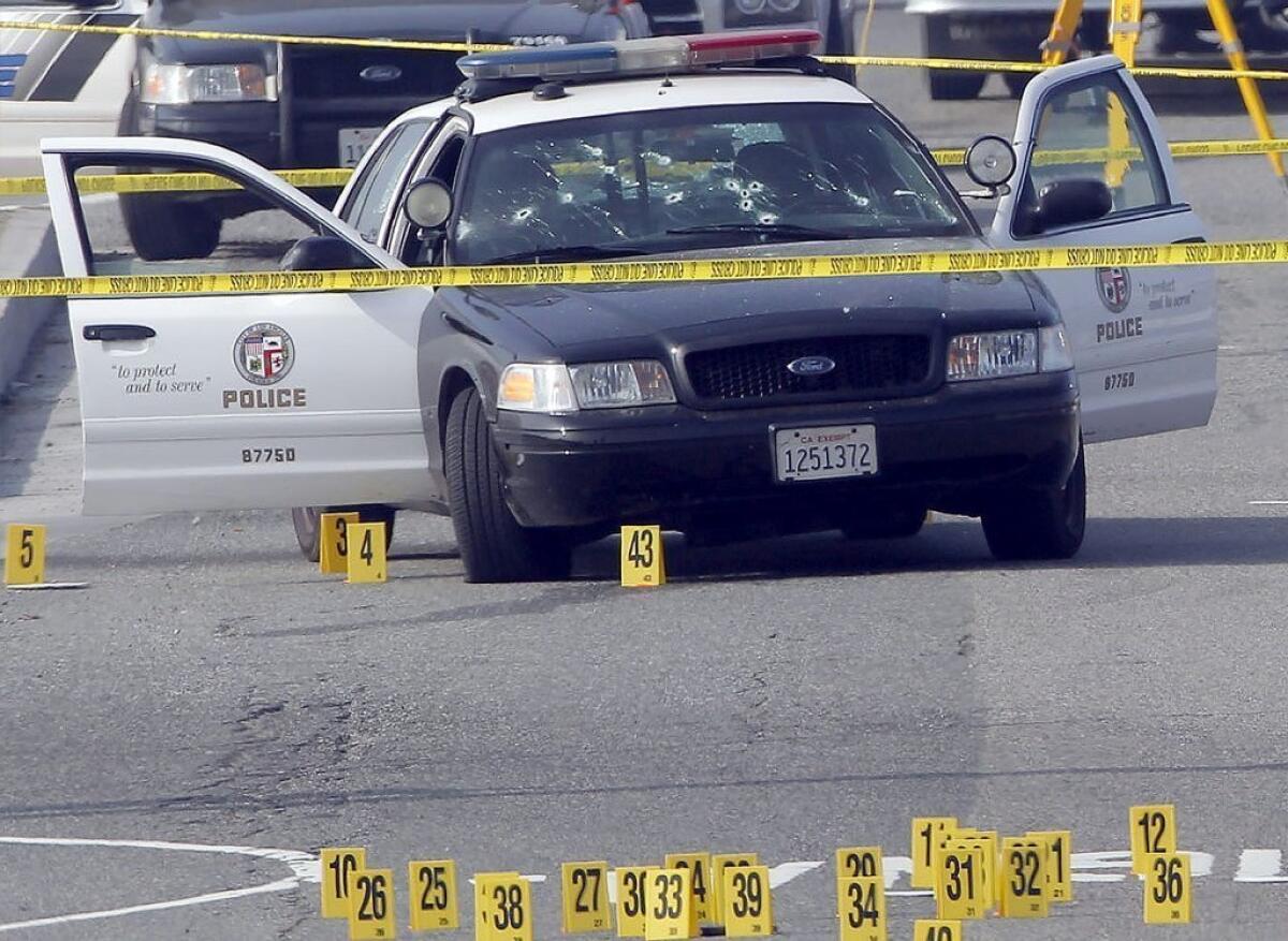 A bullet-damaged Los Angeles Police Department vehicle is taped off by police on Thursday in Corona. Former LAPD officer Christopher Dorner is suspected of shooting two officers who were sent to Corona to protect someone Dorner threatened.