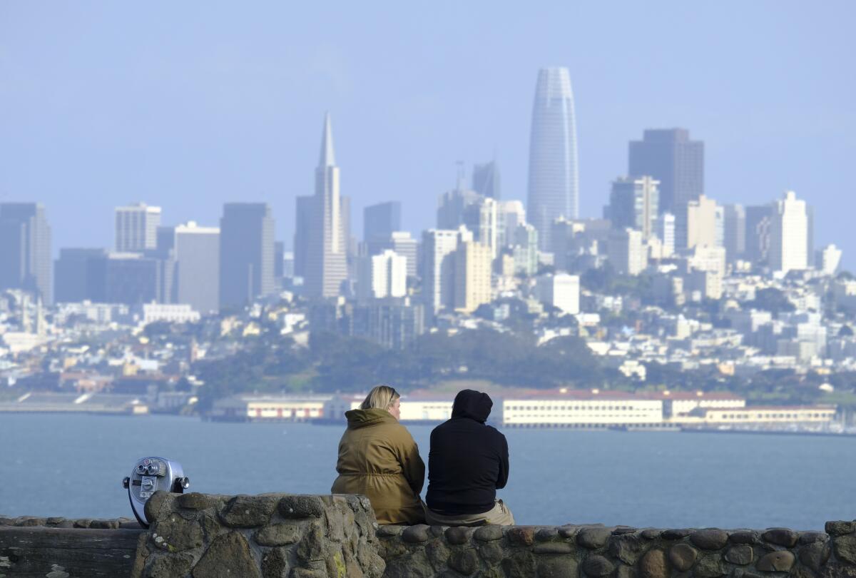 A couple sit at a vista point of the San Francisco skyline in Sausalito
