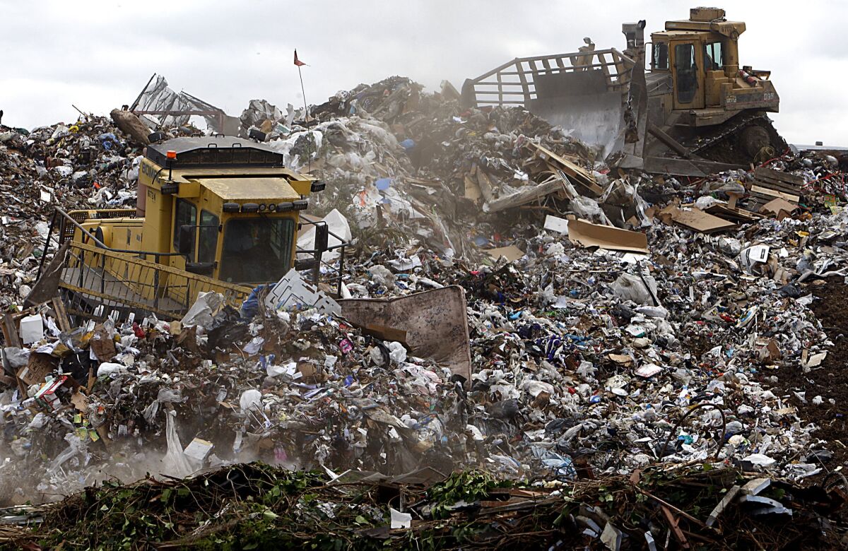 Heavy equipment operators use machinery to compact and shape mountains of trash at L.A. County's Puente Hills Landfill. (Luis Sinco / Los Angeles Times)
