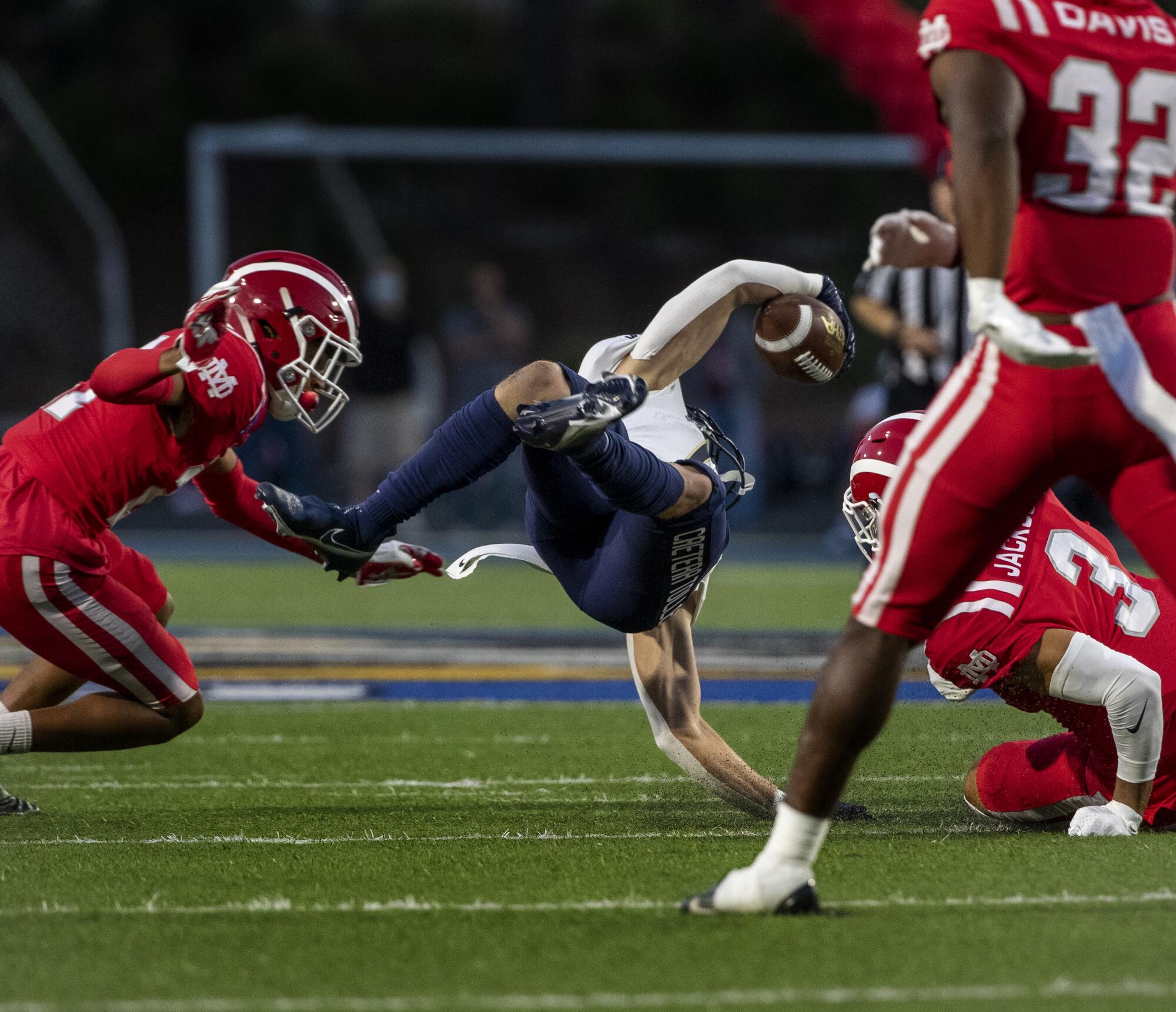 St. John Bosco wide receiver Logan Booher is upended by Mater Dei's Kassius Ashtani and Domani Jackson.