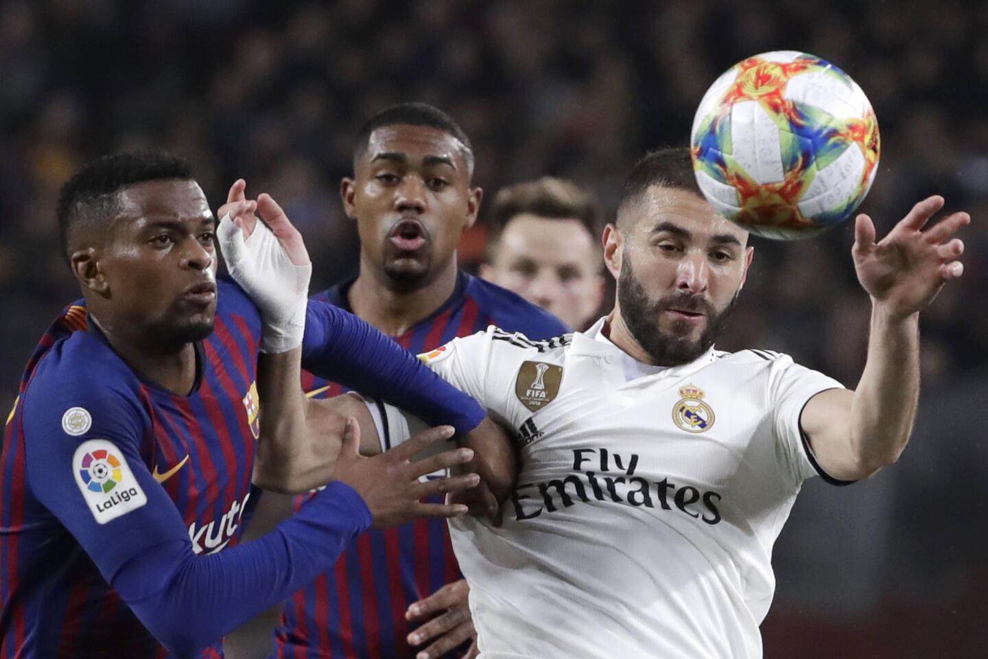 Barcelona defender Nelson Semedo uses his arms to prevent Real forward Karim Benzema from accepting a high ball during the Copa del Rey semifinal first leg soccer match between FC Barcelona and Real Madrid at the Camp Nou stadium in Barcelona, Spain, Wednesday Feb. 6, 2019. (AP Photo/Emilio Morenatti)