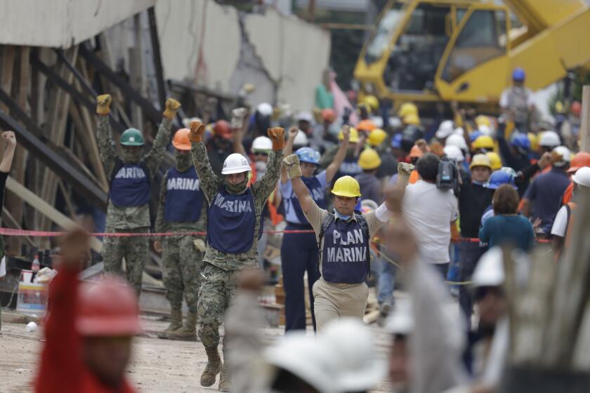 Soldiers hold up closed fists motioning for silence during rescue efforts at the Enrique Rebsamen school in Mexico City.