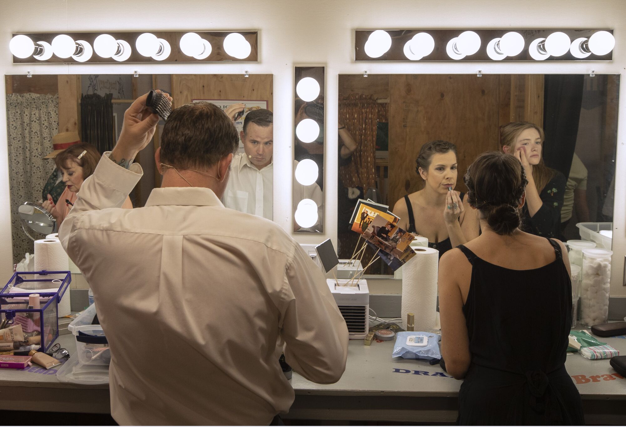 Actors look in dressing room mirrors while putting on makeup