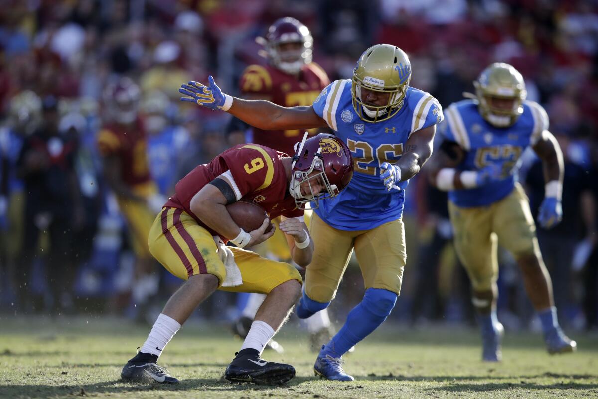 USC quarterback Kedon Slovis (9) is tackled by UCLA linebacker Leni Toailoa.