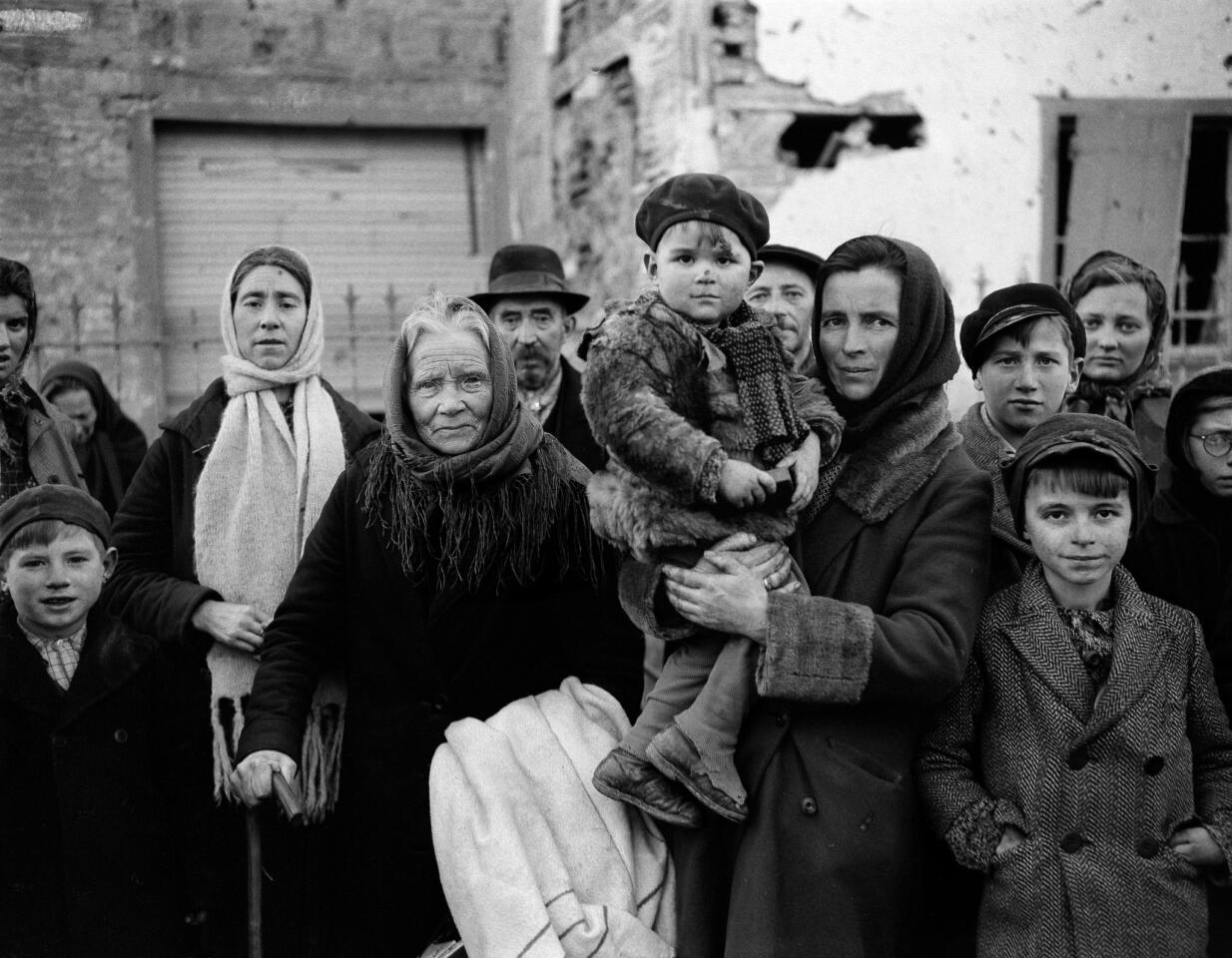 Grim-faced refugees stand in a group on a street in La Gleize, Belgium, on Jan. 2, 1945. They are waiting to be transported from the war-torn town after its recapture by American forces during the German thrust into Belgium.