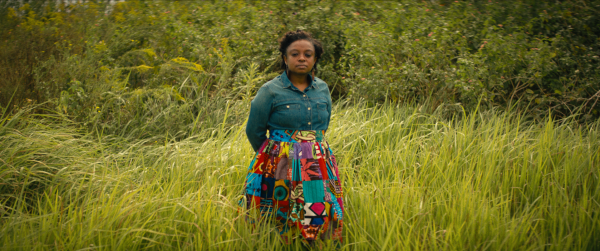 A woman in a brightly colored skirt stands for a portrait outdoors amid greenery.