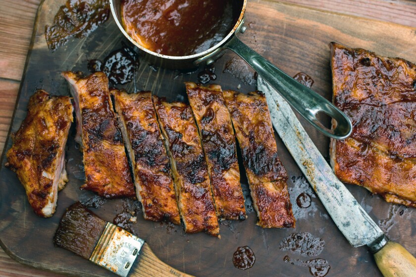 Grilled baby back ribs are seen with barbecue sauce ready to eat. 