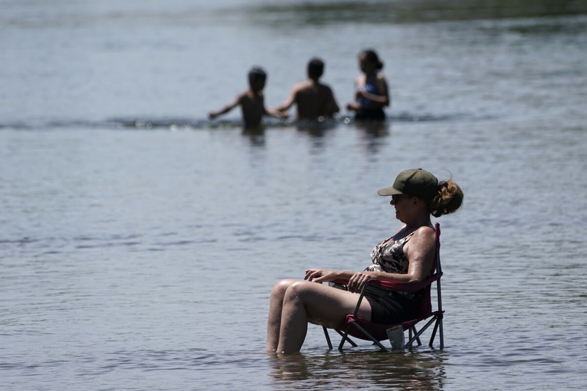 Dianna Andaya, relaxes in the cooling water of the American River as the temperature climbed over the 100 degree mark in Sacramento, Calif., Friday, June 10, 2022. Forecasters are warning of dangerously high temperatures in much of the interior of California as high pressure grips the region. (AP Photo/Rich Pedroncelli)