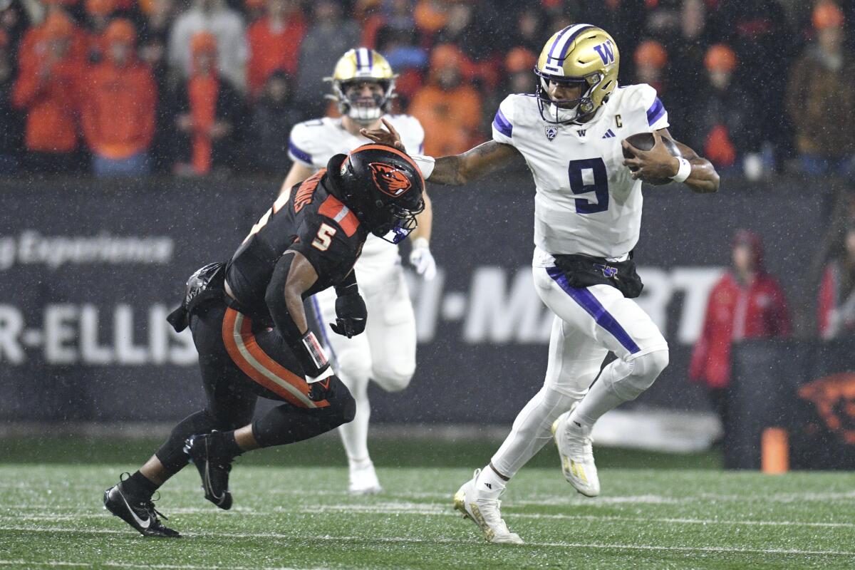Washington quarterback Michael Penix Jr. sticks his arm out as he pushes past Oregon State's Easton Mascarenas-Arnold.
