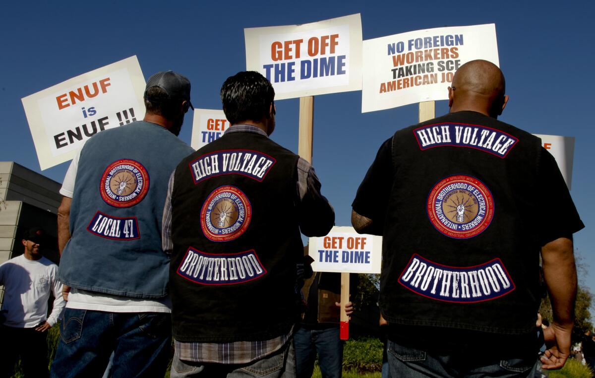Wearing their "High Voltage" union vests, members of the International Brotherhood of Electrical Workers walk a picket line Feb. 10 in front of the Southern California Edison building in Irvine. The union was showing support for workers being laid off as the company outsources technology jobs to India.