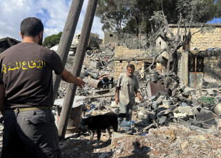 A man walks toward an elderly man amid rubble.