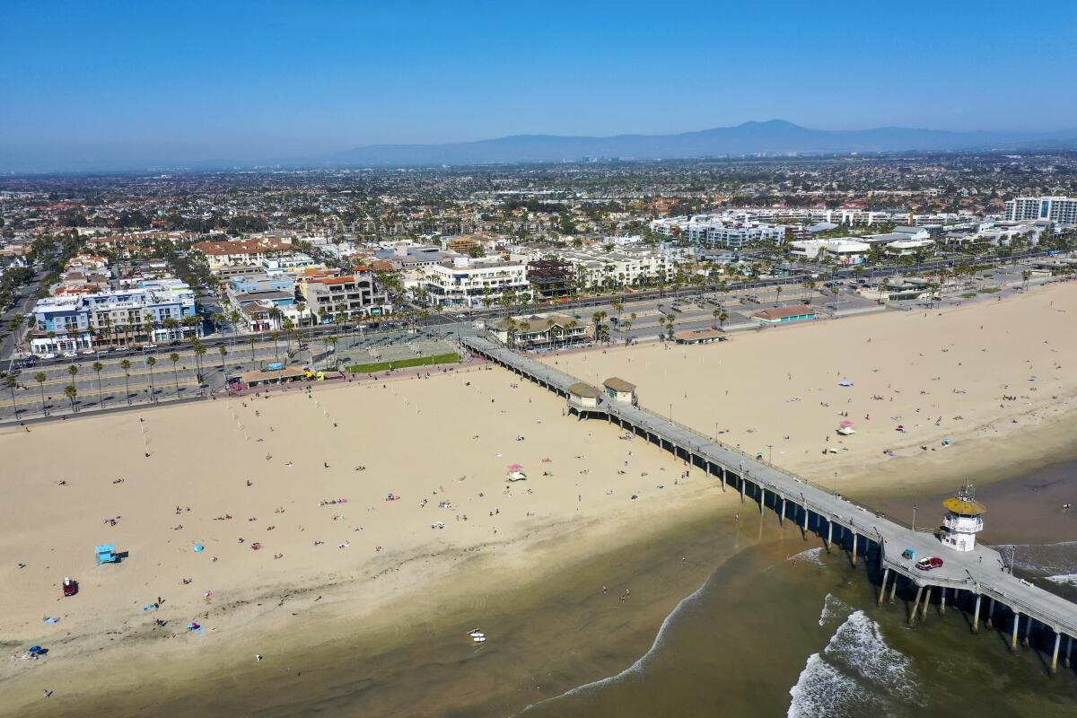 Beachgoers dot the sand in an aerial view of Huntington Beach and the pier.