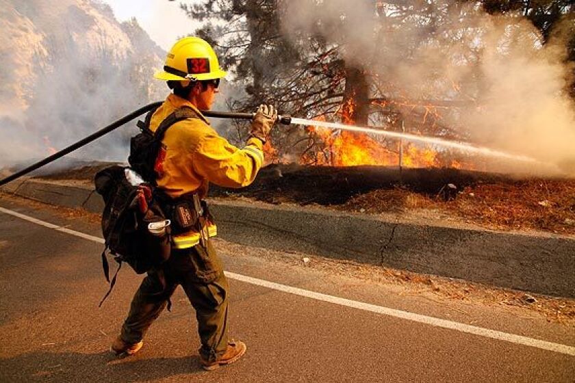 Nolan Hixon shoots water at the flames from Angeles Crest Highway.