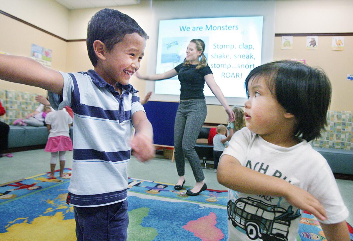 Corbin Holtzapsel, 4, of Glendale, smiles at his little brother Caleb, 2, as they dance and swing their arms during the Rhythm and Reading program at the Buena Vista Branch Library in Burbank on Thursday, March 24, 2016.