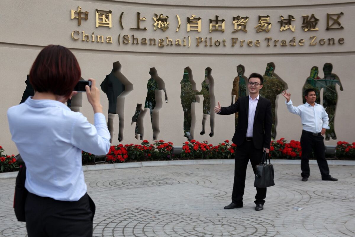 People have souvenir photos taken in front of the entrance to the Shanghai pilot free-trade zone in Shanghai on Sunday.