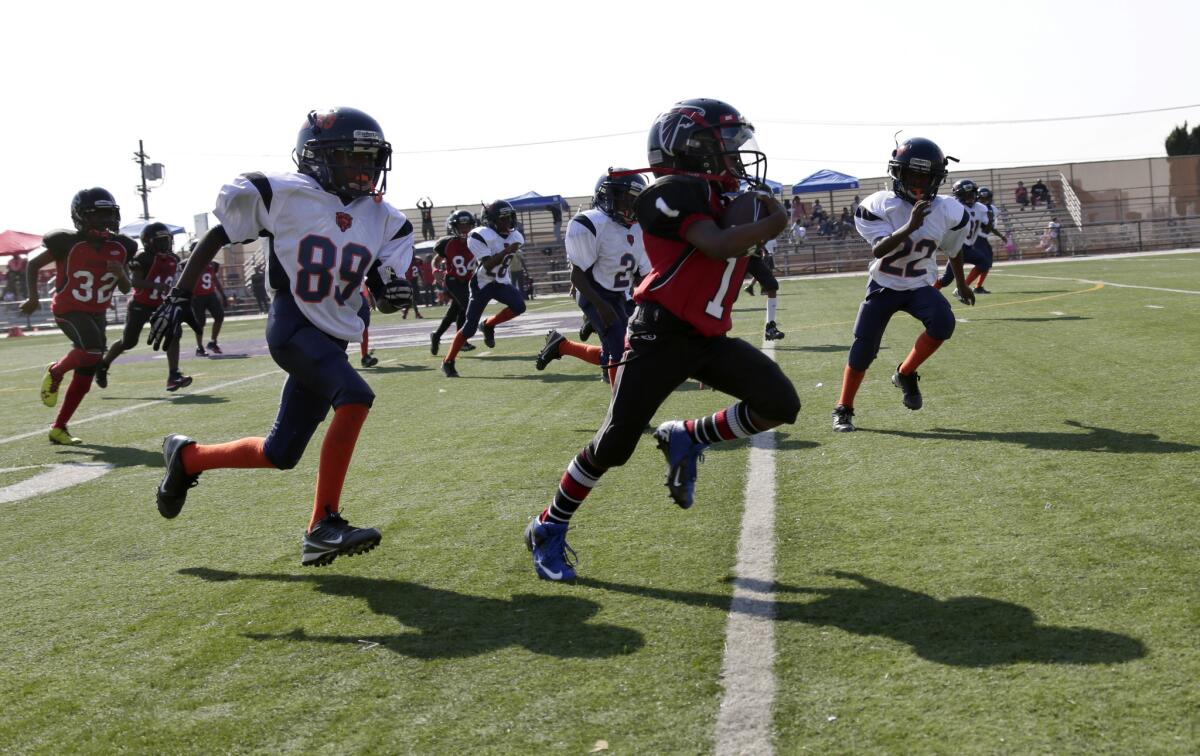 Good wholesome fun, or a threat to kids' health? The LAPD-coached youth football team Watts Bears (in white) pursue a member of the Southern California Falcons during a 2013 game. The players are 7 to 9 years old.
