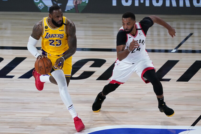 Los Angeles Lakers' LeBron James (23) drives into Toronto Raptors' Norman Powell (24) during the first half of an NBA basketball game Saturday, Aug. 1, 2020, in Lake Buena Vista, Fla. (AP Photo/Ashley Landis, Pool)