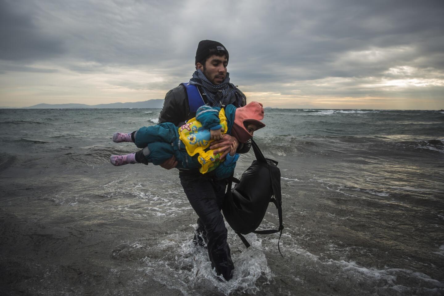 Un hombre carga a un niño mientras tratan de llegar a la costa tras caerse al mar al desembarcar de un bote en el que cruzaron parte del mar Egeo desde Turquía hasta la isla griega de Lesbos junto con otros migrantes. La guardia costera griega dijo que ha rescatado a 217 migrantes de las aguas desde el inicio del nuevo año, en cuatro instancias separadas.(Foto AP/Santi Palacios)