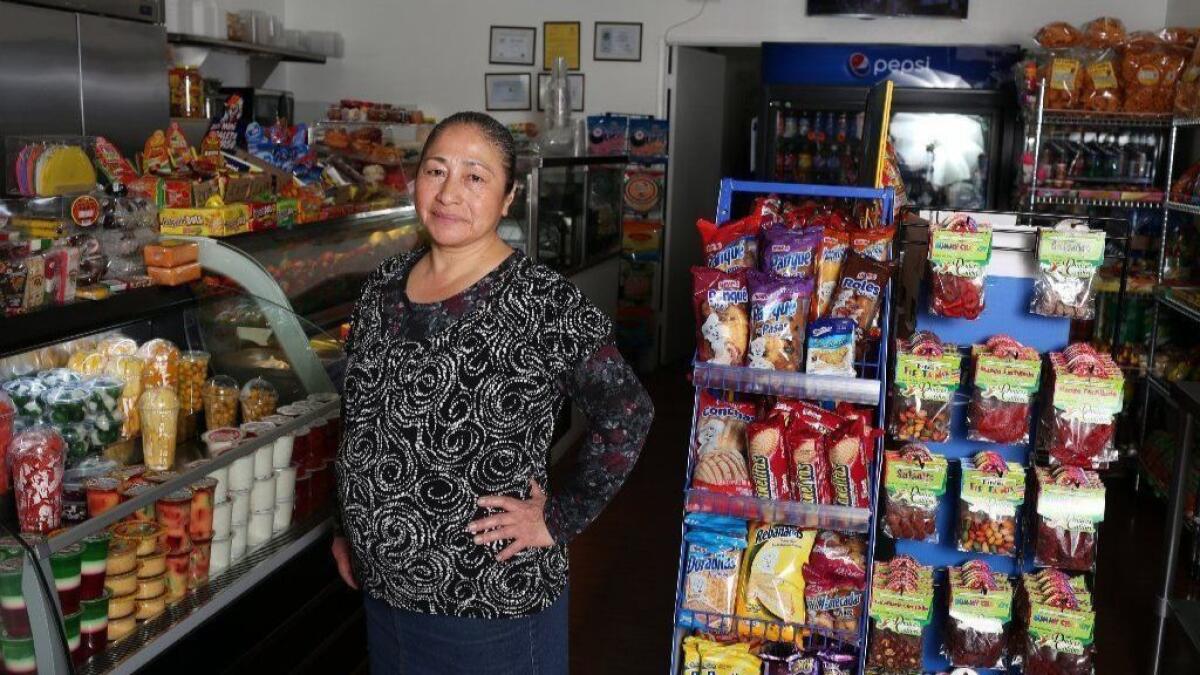 Elizabeth Alcarraz stand in an aisle at "Noemi's Fruits," her West Carson fruit shop.