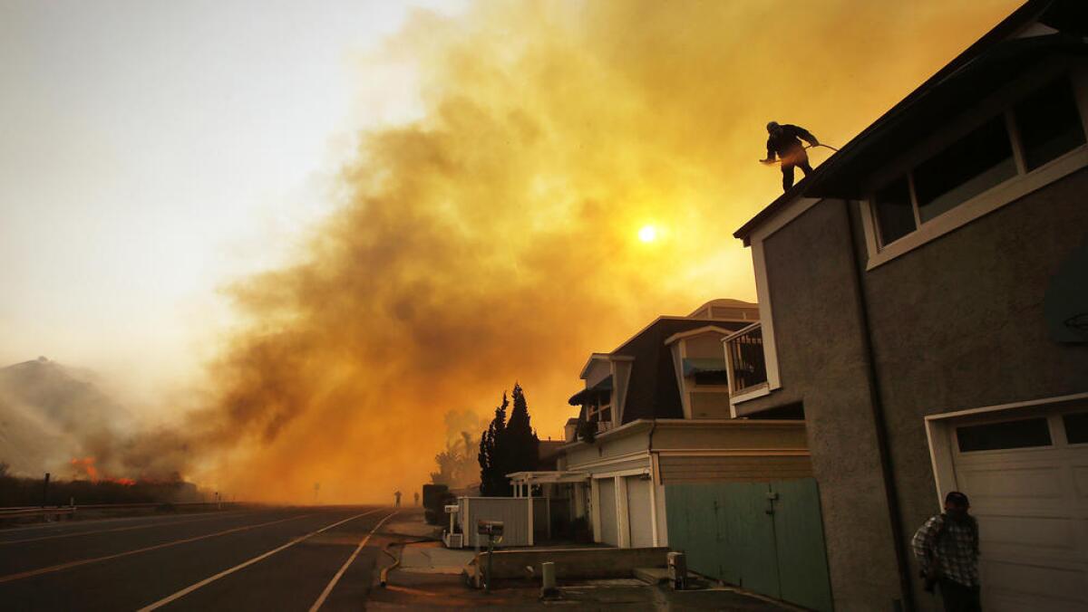 People brave rooftops to extinguish embers from spot fires between the 101 Freeway and Faria Beach as the Thomas fire threatens homes.