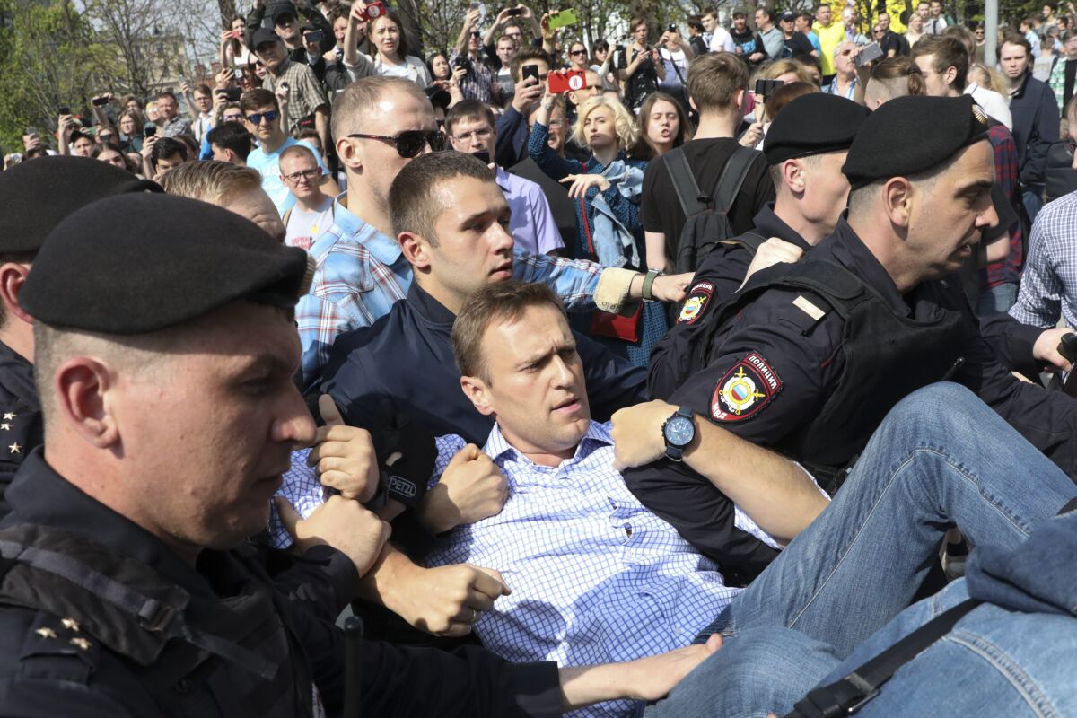 FILE - In this May 5, 2018, file photo, Russian police carry opposition leader Alexei Navalny, center, from a demonstration against President Vladimir Putin in Pushkin Square in Moscow, Russia. Attempts over the years to silence Kremlin critic Navalny have all failed so far. Now Navalny is in a coma in a Berlin hospital after suffering what German authorities say was a poisoning with a chemical nerve agent while traveling in Siberia on Aug. 20. (AP Photo, File)