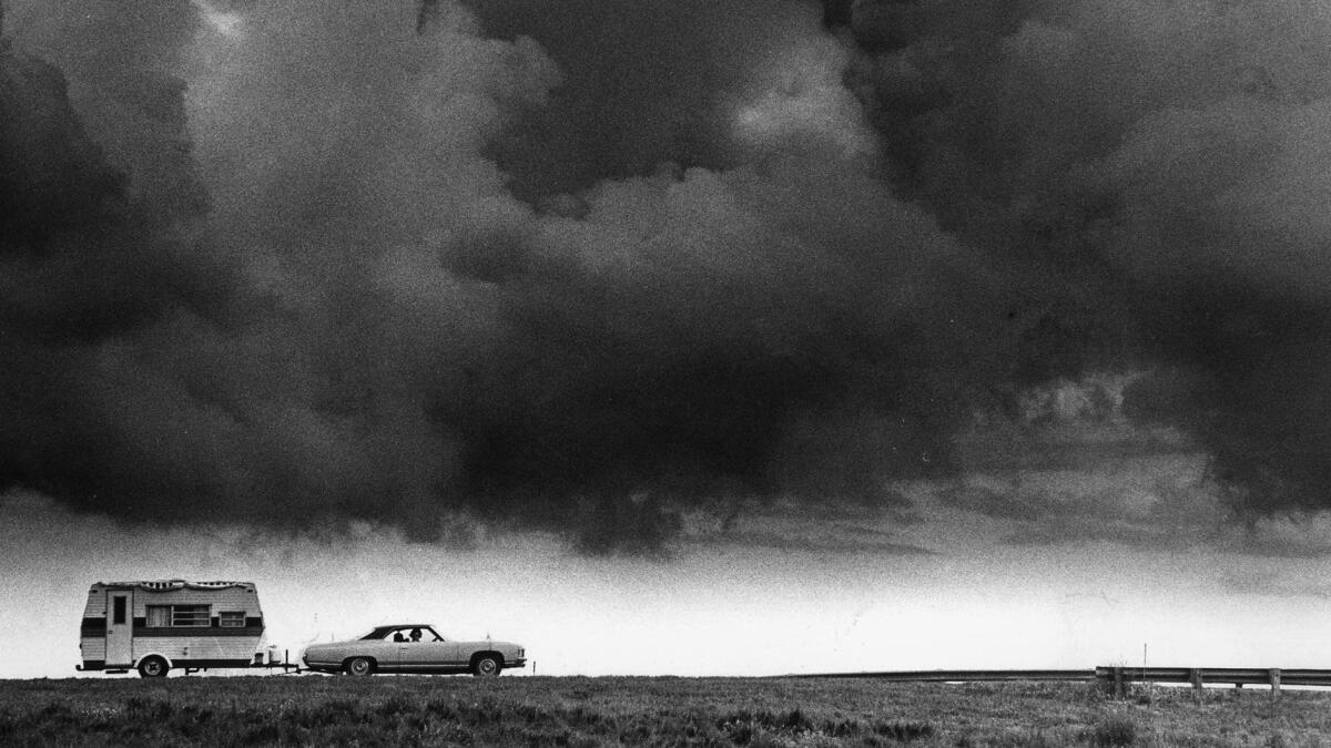 June 28, 1977: Under heavy clouds, a car and trailer zip along a stretch of Route 66, converted to Interstate 40, near Sayre, Okla. This photo was published on Page One of the July 24, 1977, Los Angeles Times.