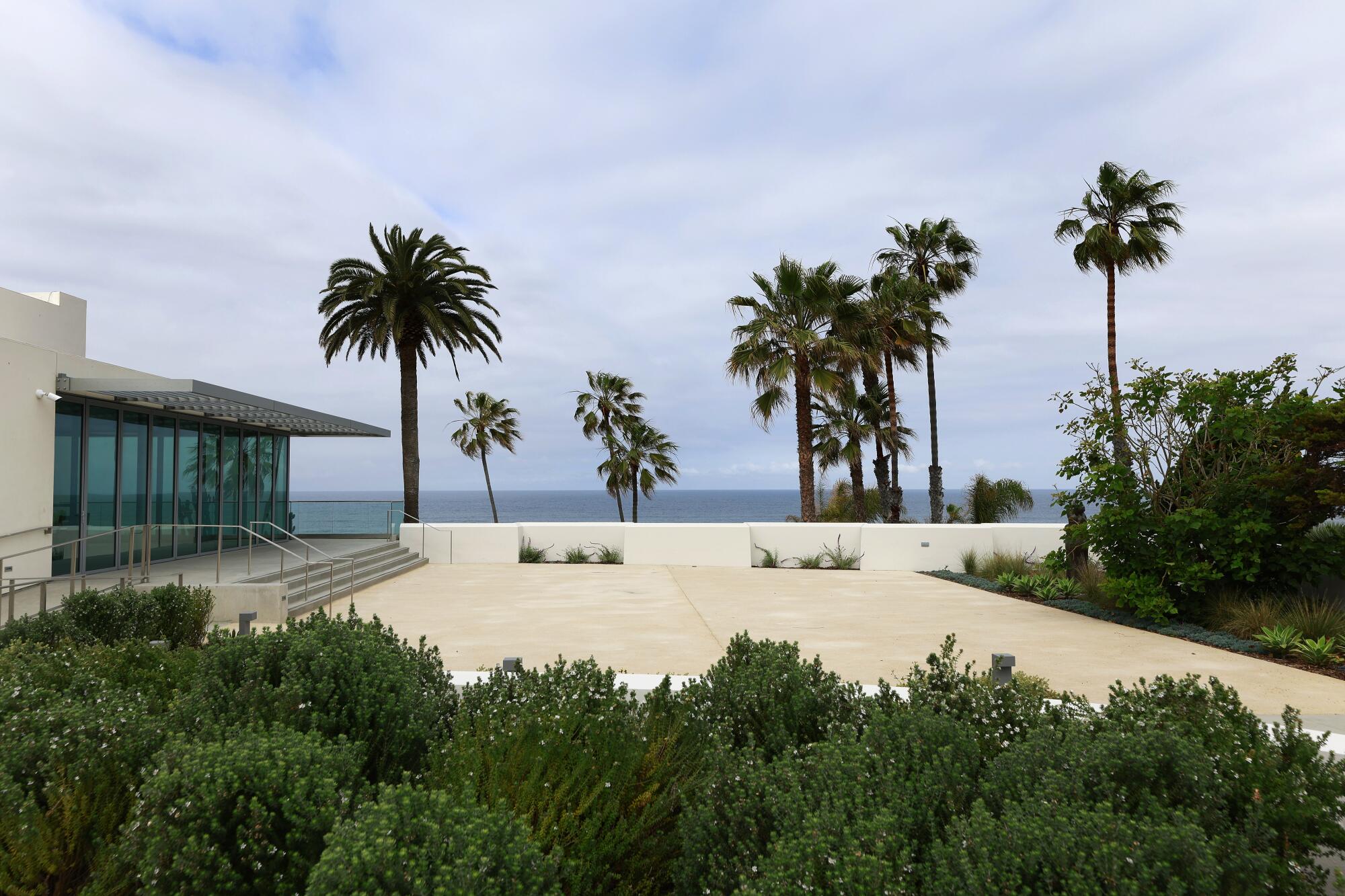 An ocean view terrace is fringed by palm trees.