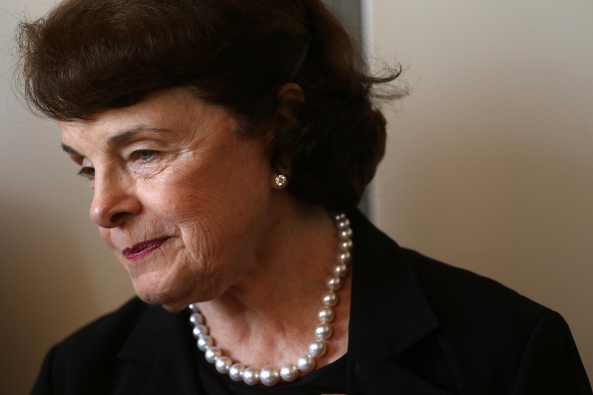 Sen. Dianne Feinstein looks to the side while wearing a dark top and pearls.