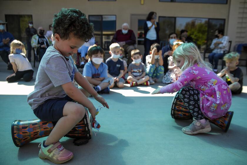 Van Nuys, CA - March 18: Landon Seror, 4, left, and Jacqueline Morrison, 4, play bongo drums at music hour at ONEgeneration Child Daycare & Adult Daycare on Friday, March 18, 2022 in Van Nuys, CA. (Irfan Khan / Los Angeles Times)