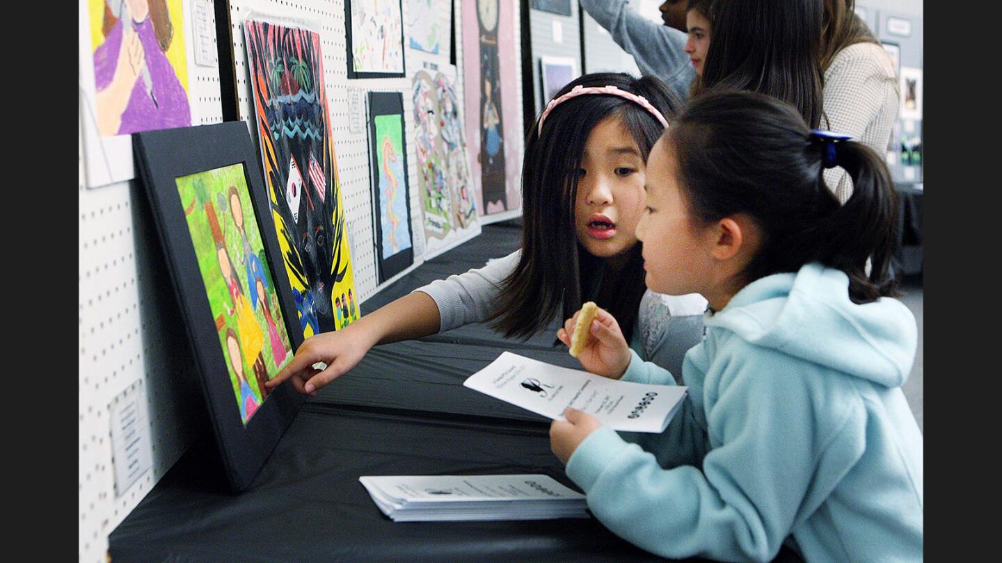 Andrea Chen, 7, and Angel Song, 7, look at details in Angel's artwork at the La Cañada PTA Council Reflections Program 2016-2017 reception and awards ceremony at the LCUSD Board Room on Wednesday, February 22, 2017. The theme, used by artists from kindergarten to twelfth grade, was "What Is Your Story?" and included audio art, video, photography, and artwork.