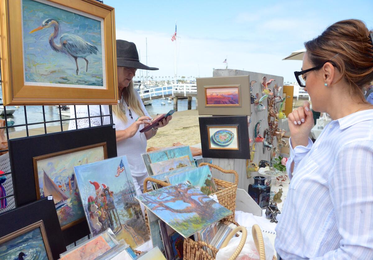 Diana Johnson admires her purchase as artist Kirsten Anderson tallies up a sale at the Balboa Island Artwalk.
