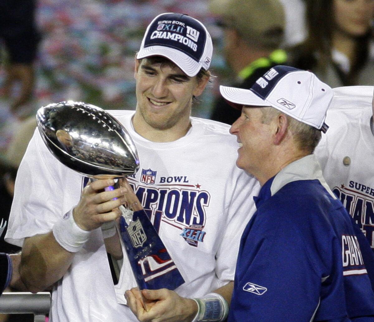 Giants'ın oyun kurucusu Eli Manning ve antrenör Tom Coughlin, Super Bowl XLII'yi kazandıktan sonra Vince Lombardi Kupasını inceliyor.