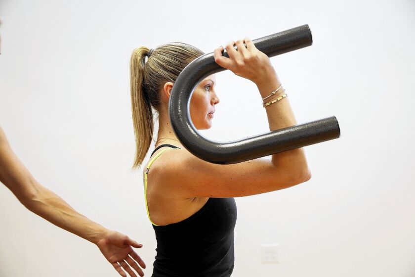 Rachel DeLuca works out with a U-shaped metal bar during a morning cardio fusion class of dance, barre and Pilates at Best U Studio in West Hollywood.