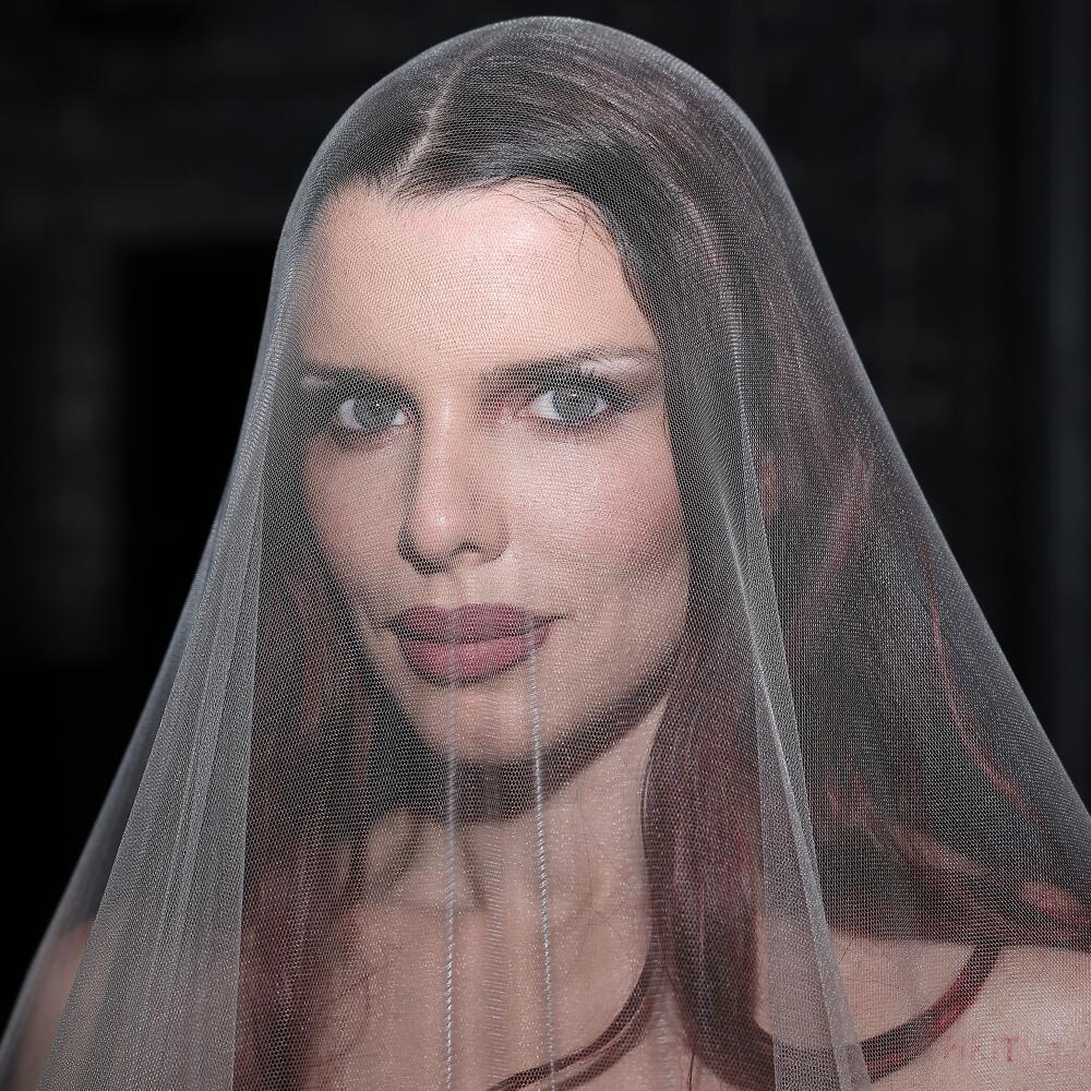 A woman wearing a see-through veil at a fashion event.
