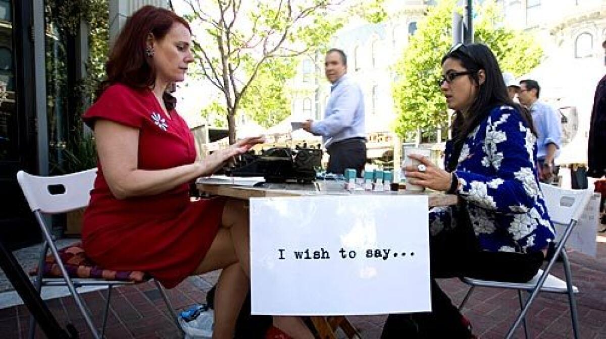 Performance artist Sheryl Oring, left, types a postcard for resident Katie Kurtz on an Oakland street corner.